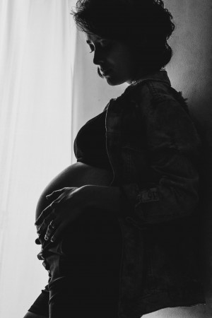 pregnant women standing in the dark with migraine