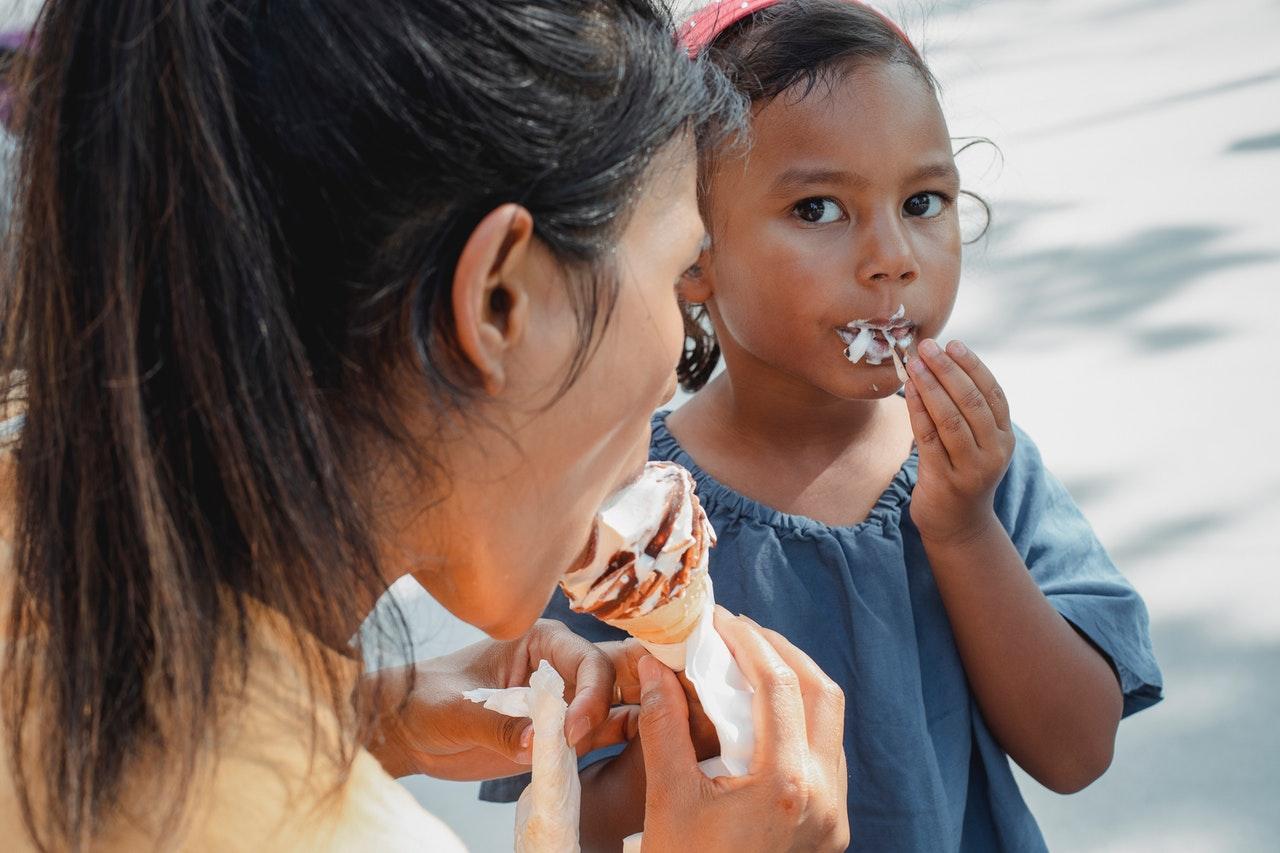 Child eating ice cream with parent