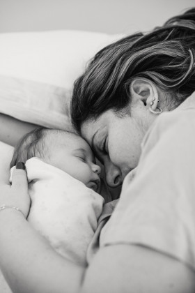Mum hugging newborn in bed