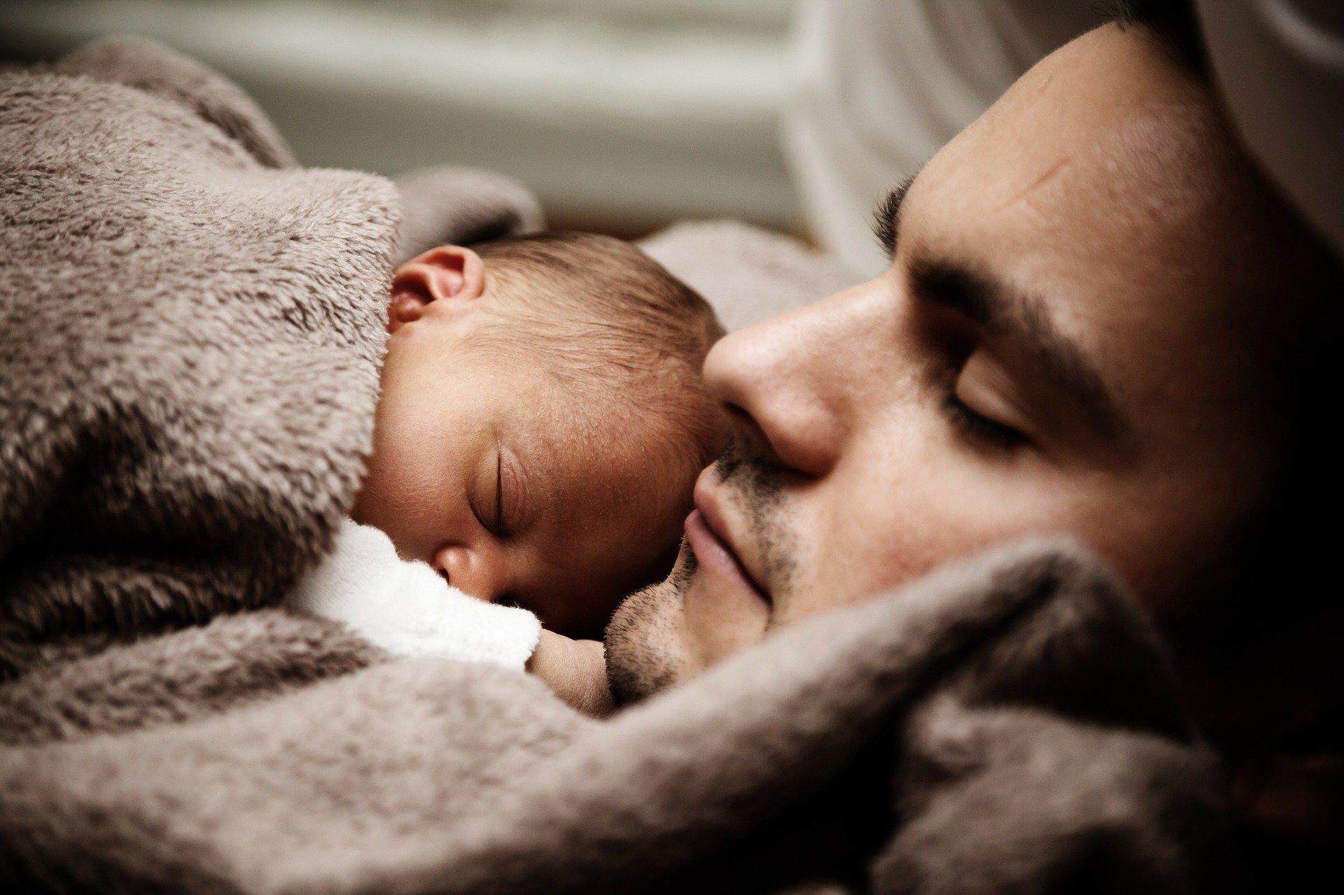 Dad sleeping with newborn baby